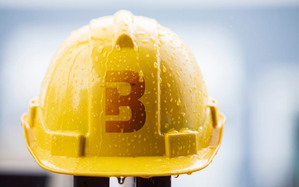 Žlutá helma se symbolem B